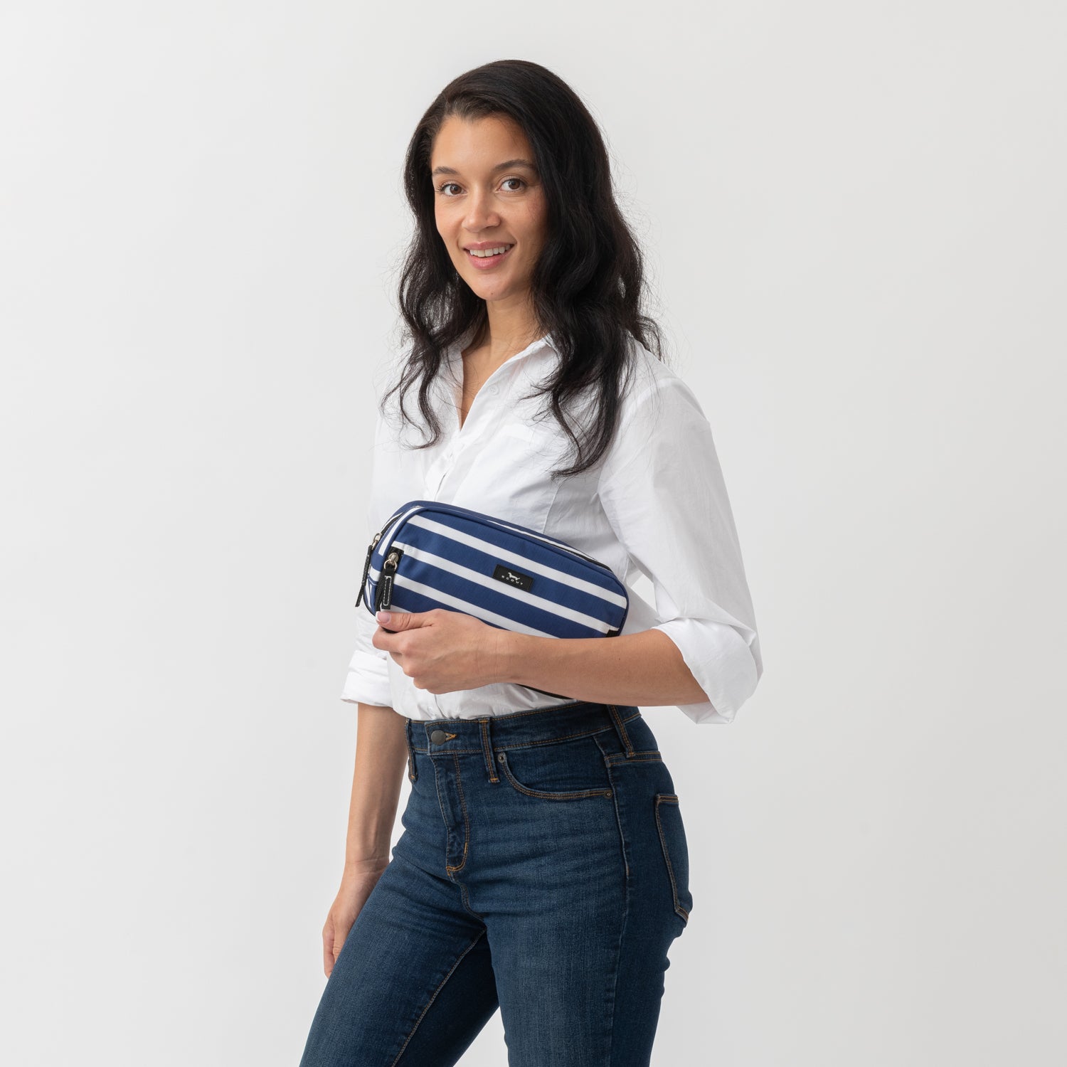 Woman holding a blue and white striped pouch against a plain background