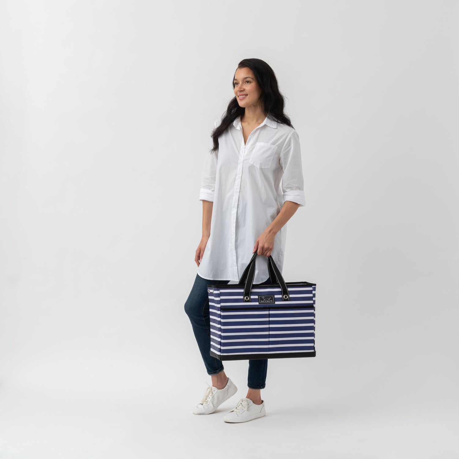 Woman holding a striped bag against a white background