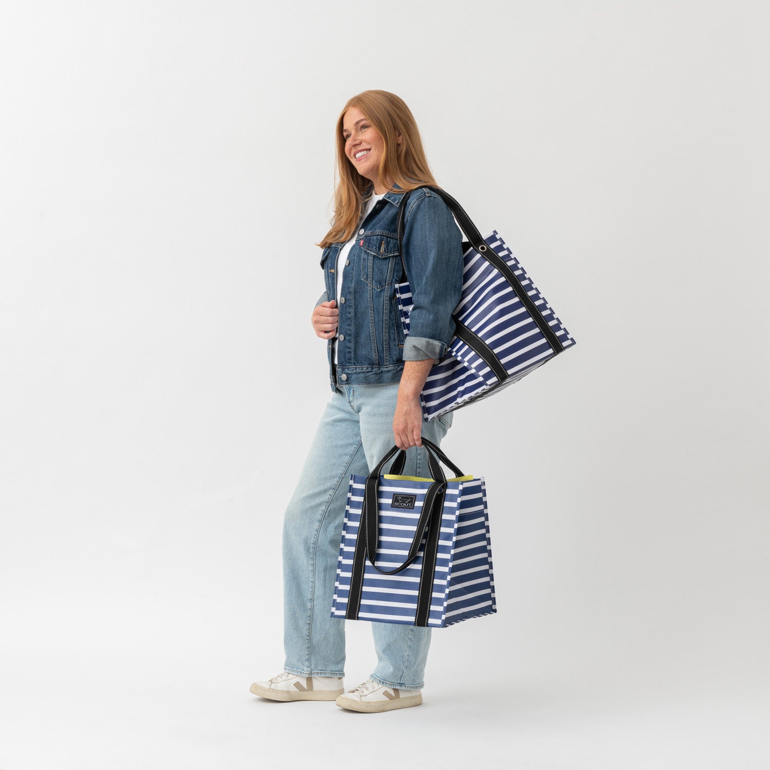 Woman holding two striped bags against a white background