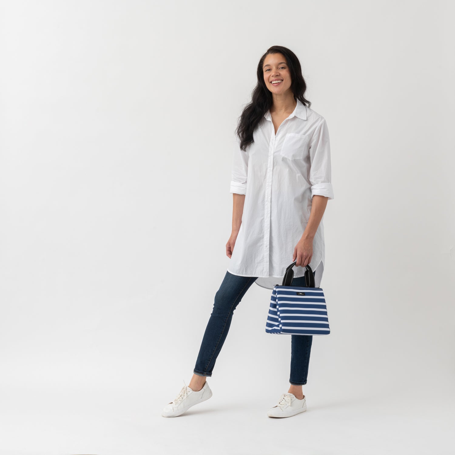 Woman holding a striped lunch cooler on a white background
