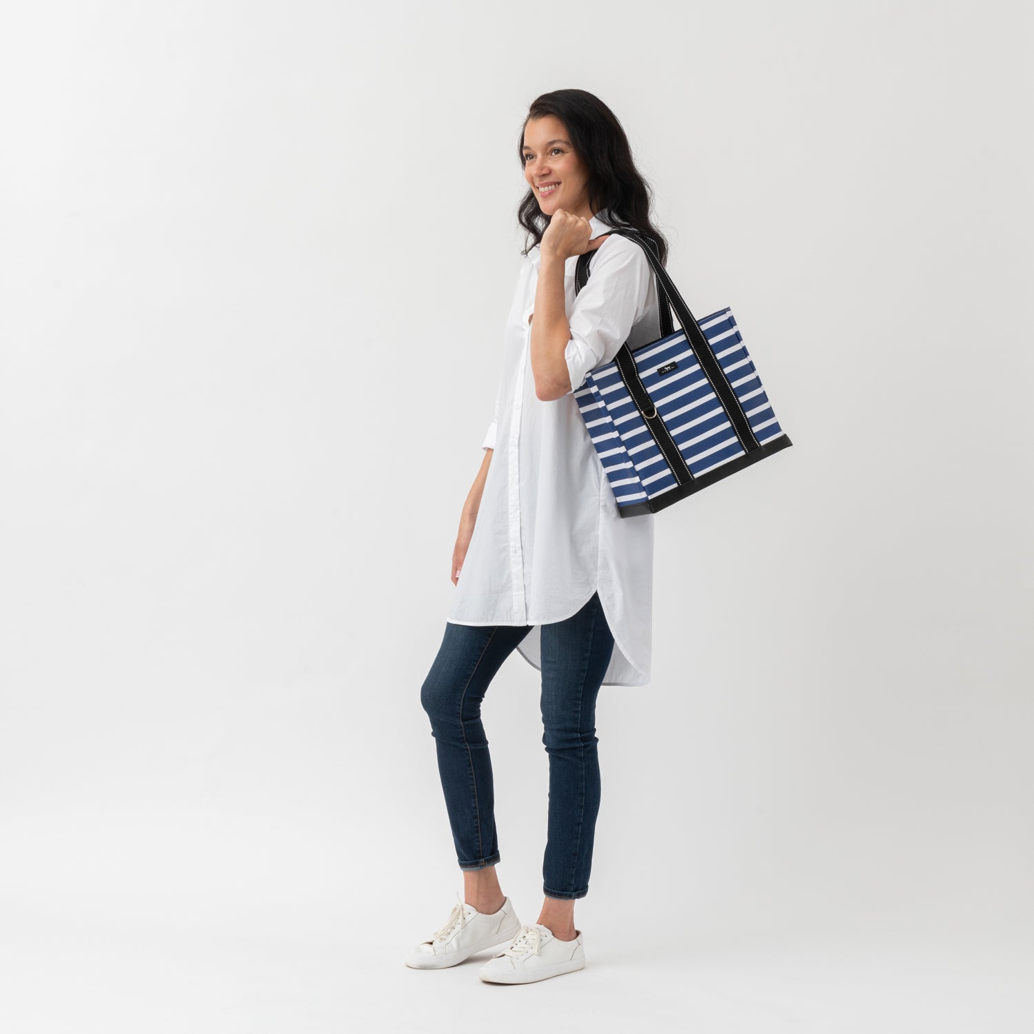 Woman holding a blue and white striped tote bag on a white background