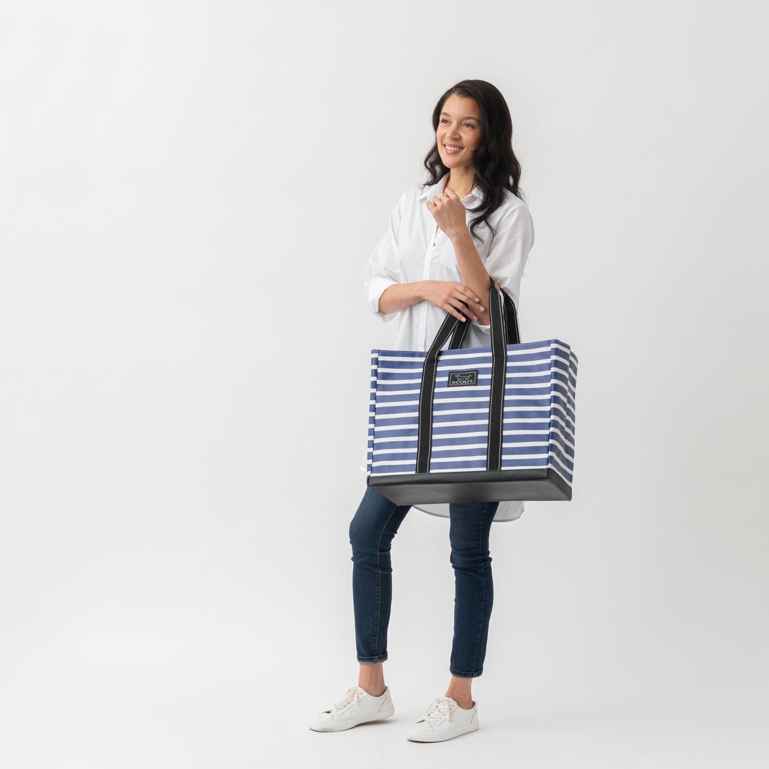 Woman holding a blue and white striped tote bag on a white background