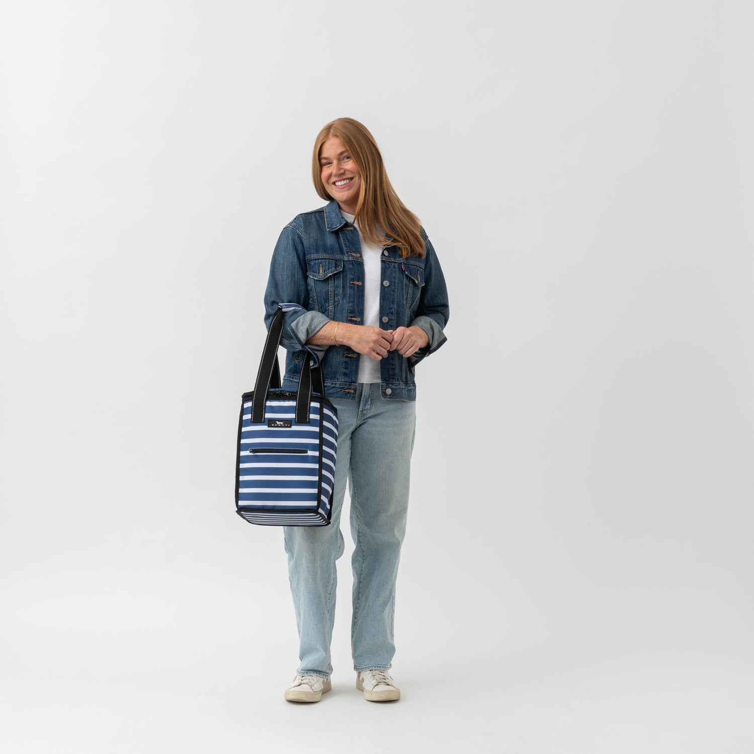 Woman holding a striped bag against a white background