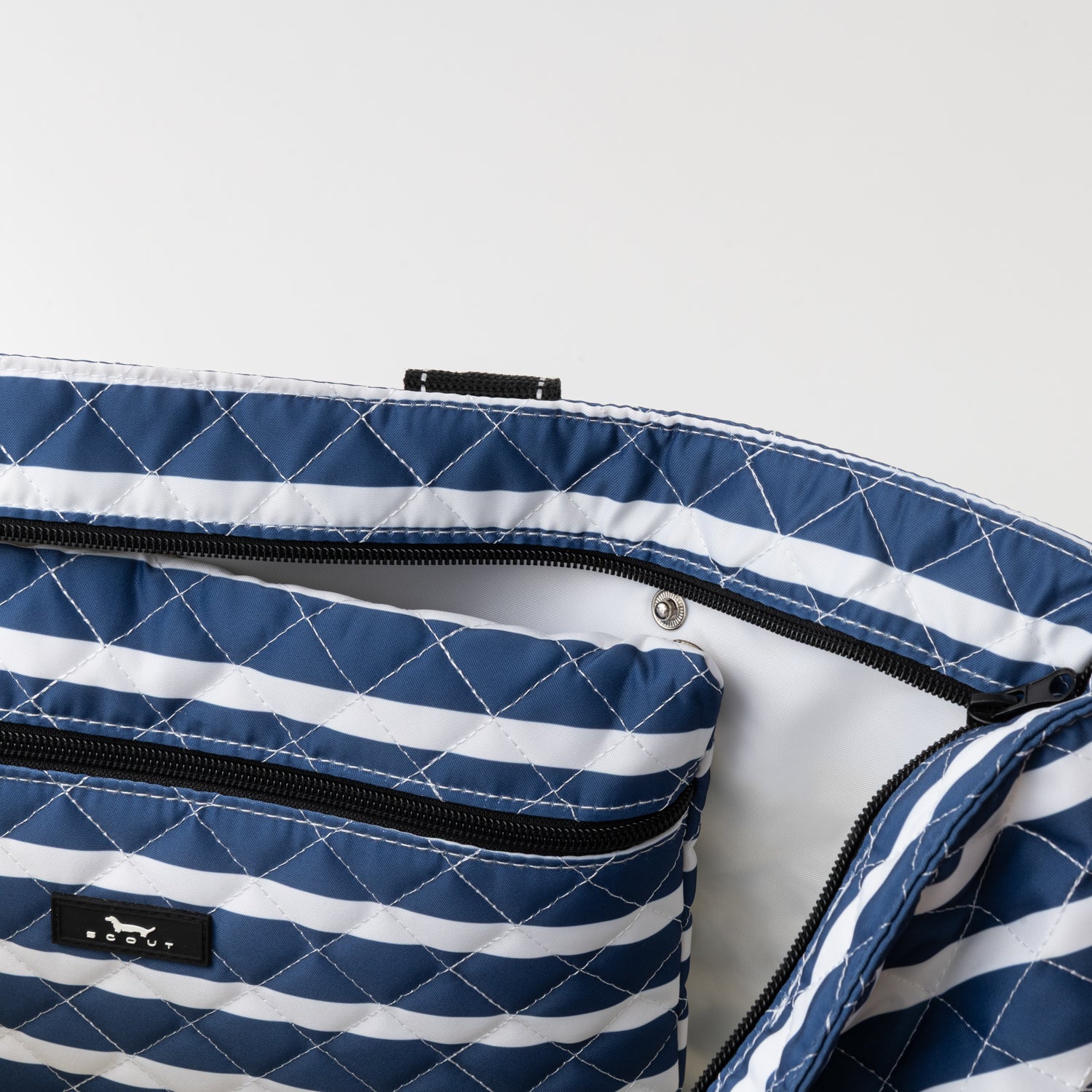 Blue and white striped quilted bag with a visible brand label on a light gray background