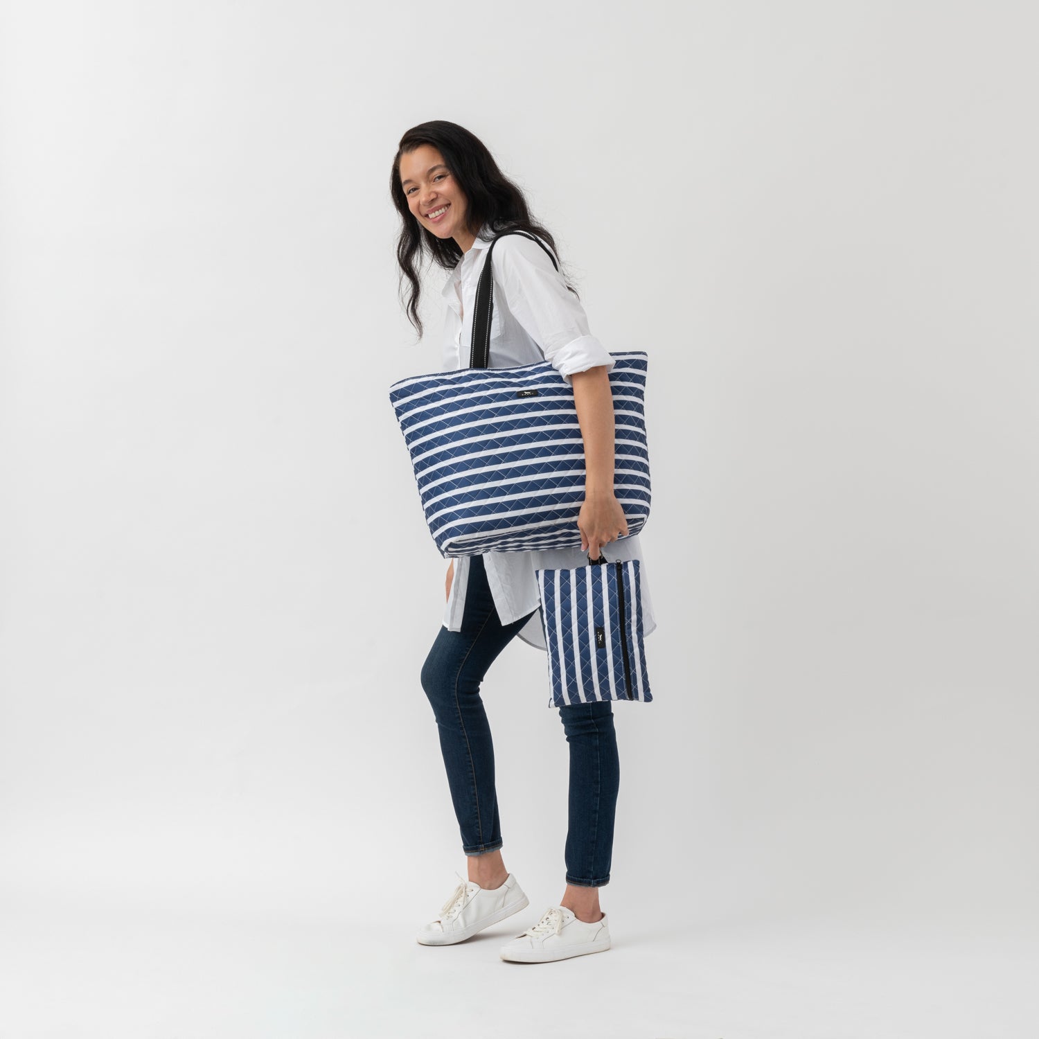 Woman holding a large blue and white striped bag on a white background