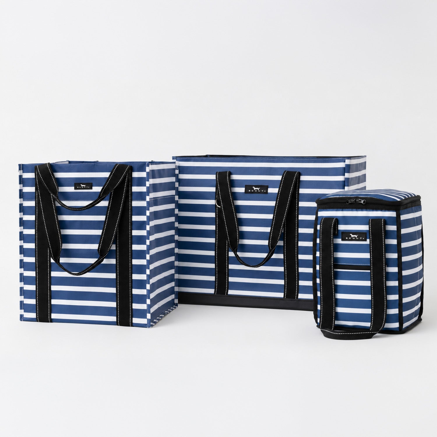 Three striped soft-sided bags in blue, navy, and white with black handles and trim, arranged on a light gray studio background.