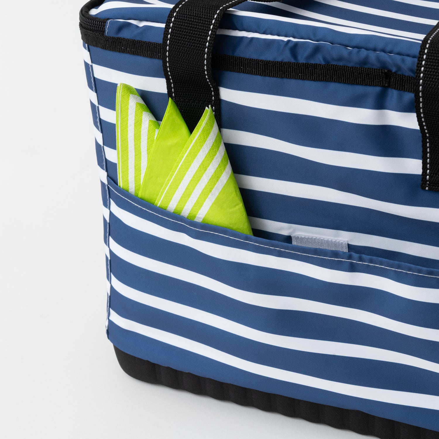 Blue and white striped tote bag with a green napkin peeking out on a light gray background