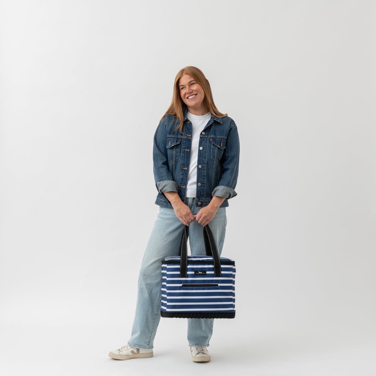 Person holding a striped bag against a white background
