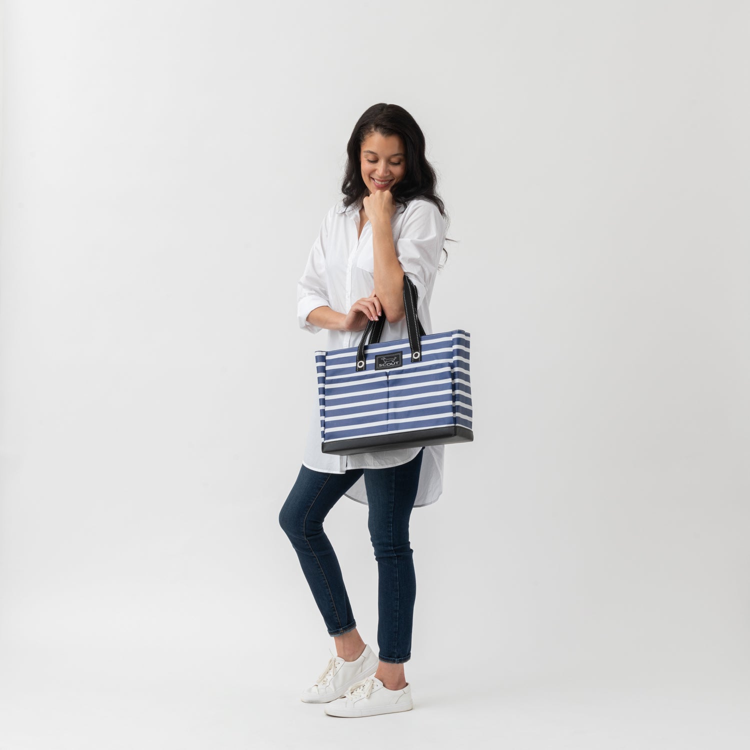 Woman holding a blue and white striped tote bag on a white background