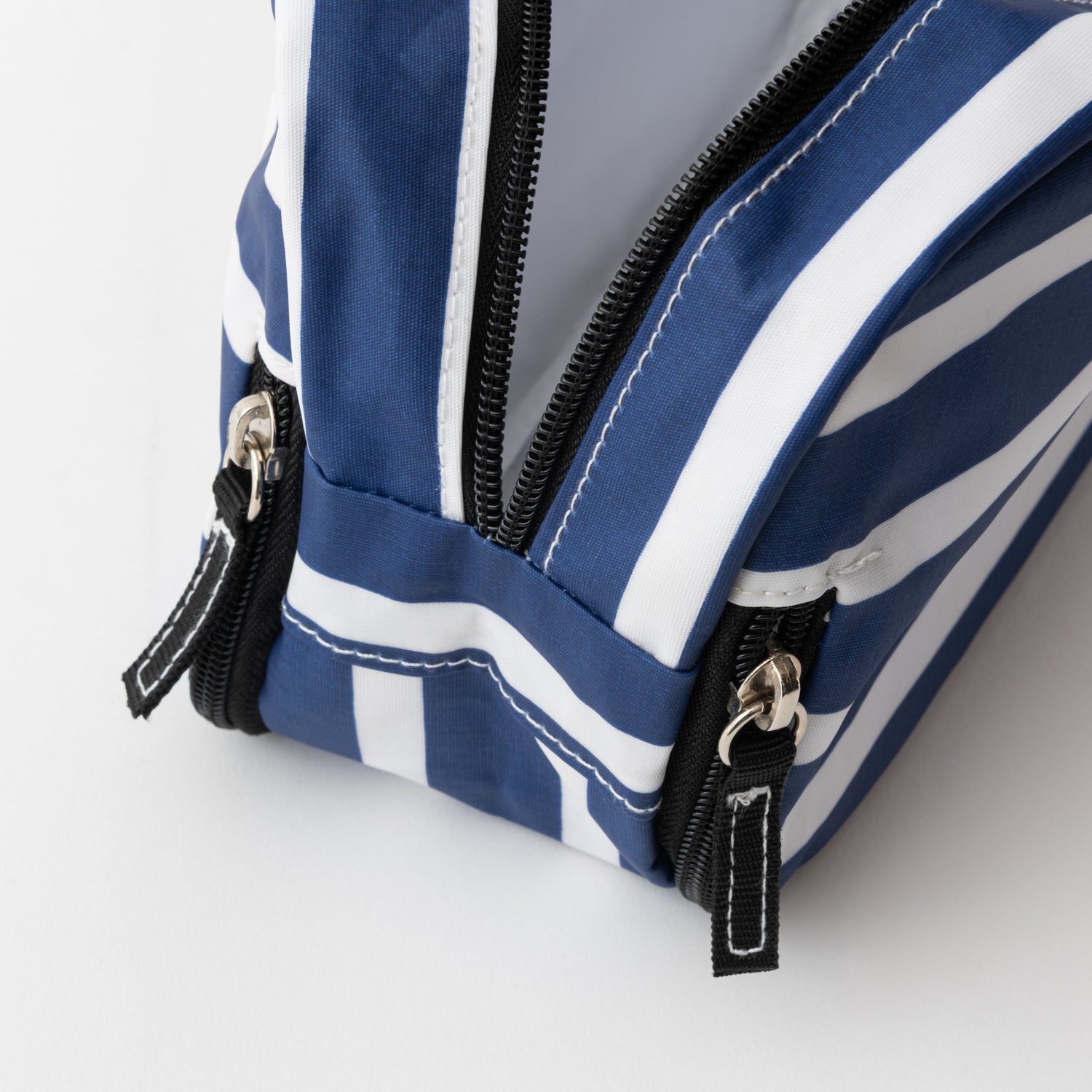 Blue and white striped bag with zippers on a light gray background