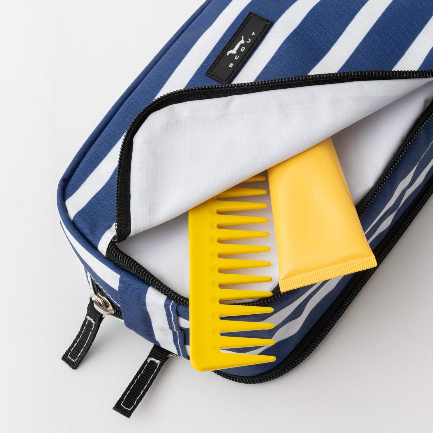 Yellow comb in a blue and white striped bag on a light gray background