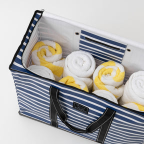 Blue and white striped bag filled with rolled towels on a white background