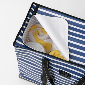 Blue and white striped tote bag with towels inside on a light gray background