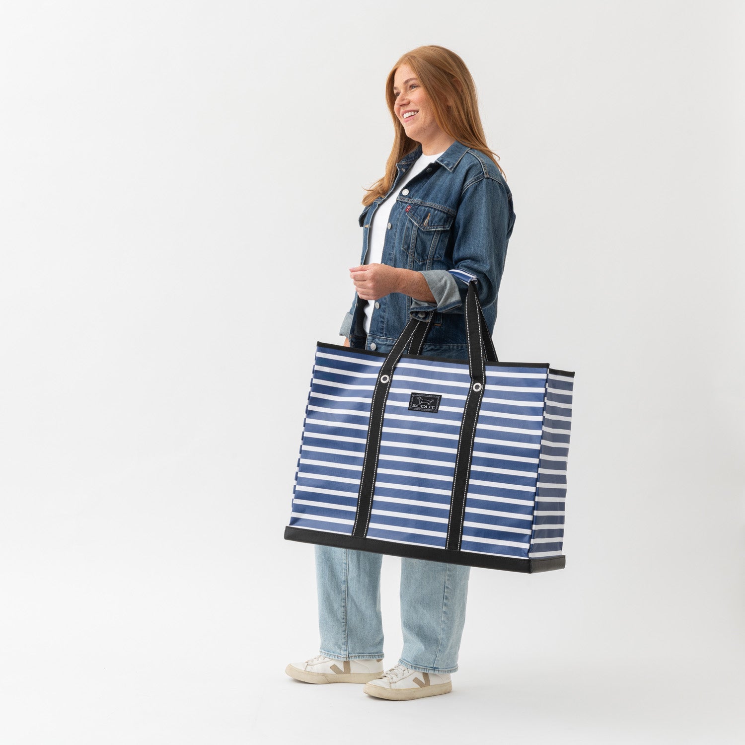 Person holding a blue and white striped tote bag on a white background