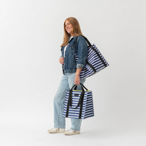 Woman holding two striped bags against a white background