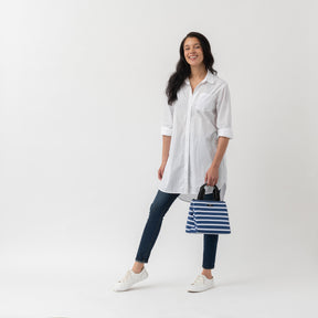 Woman holding a striped lunch cooler on a white background