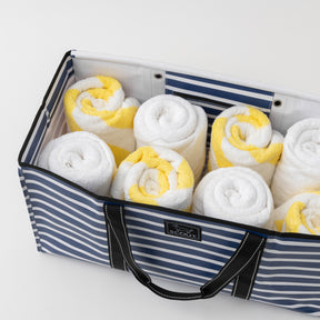 Blue and white striped bag filled with rolled towels on a light gray background