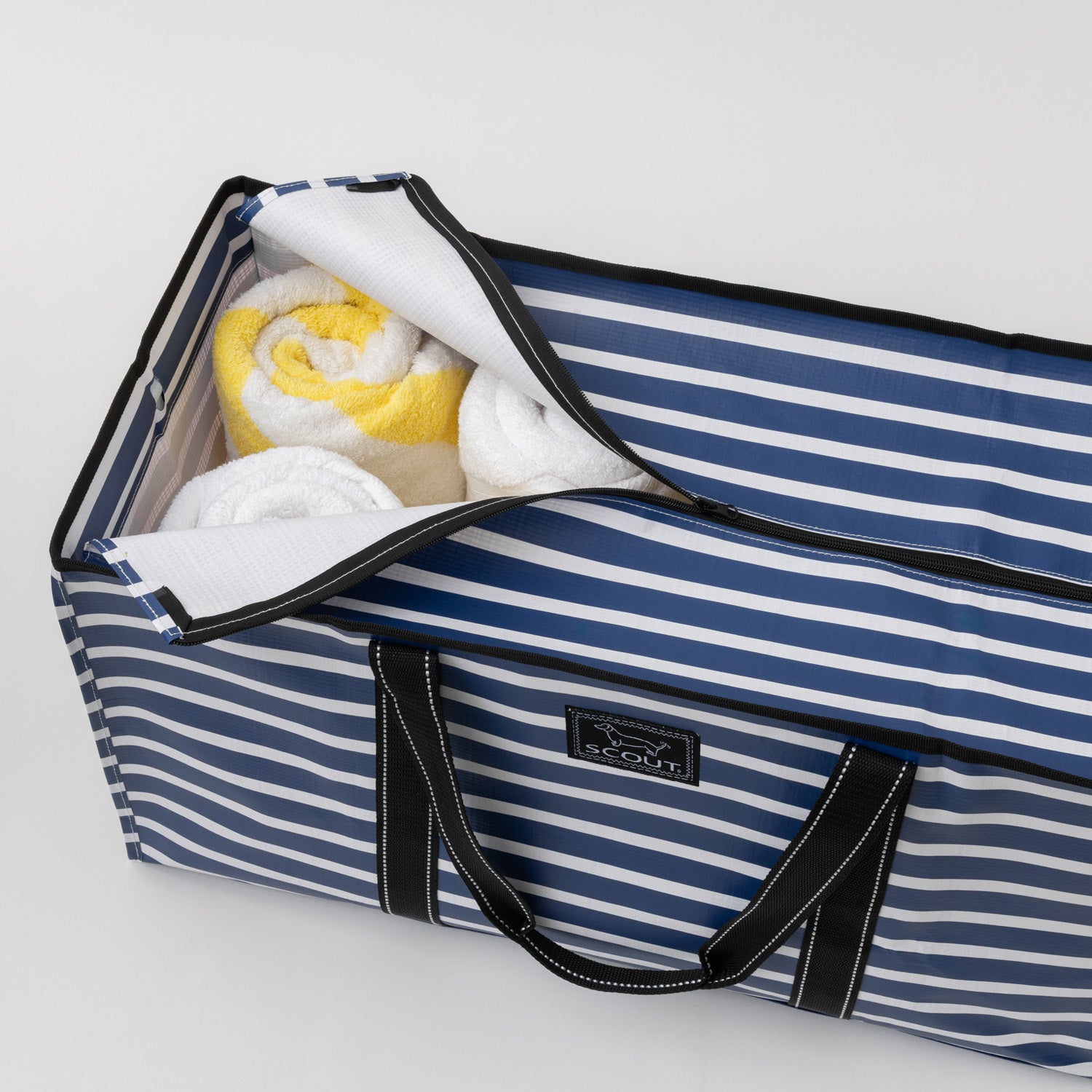 Striped storage bag with towels inside on a light gray background