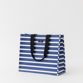 Blue and white striped tote bag with black handles on a light gray background