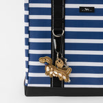 Blue and white striped bag with a decorative keychain on a white background