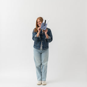 Woman holding a striped bag against a white background
