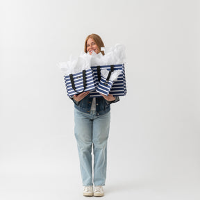 Person holding two large striped bags against a white background