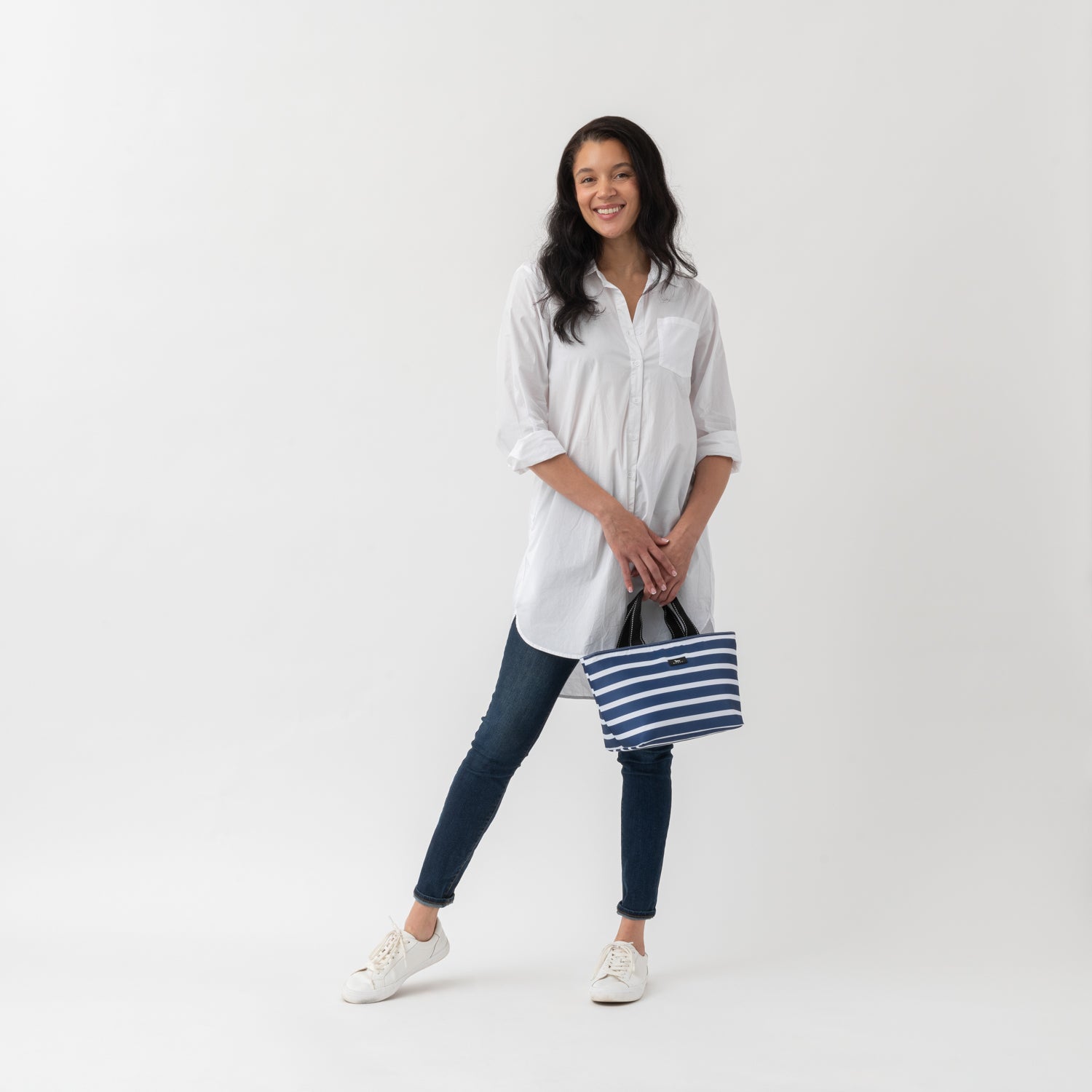 Woman holding a striped bag against a white background