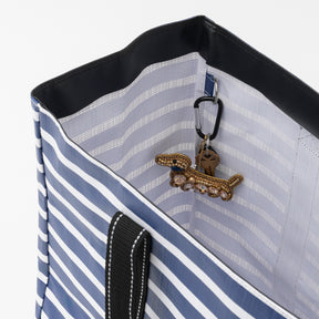 Close-up of a blue and white striped bag with a dog-shaped keychain on a light gray background
