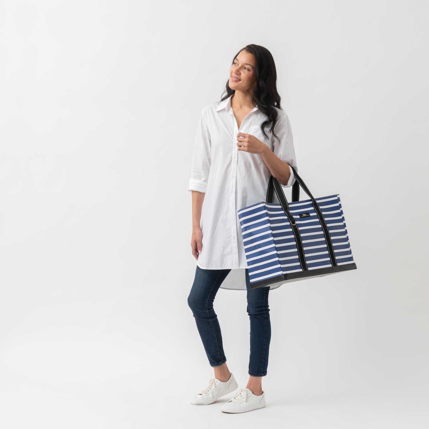 Woman holding a blue and white striped tote bag on a white background
