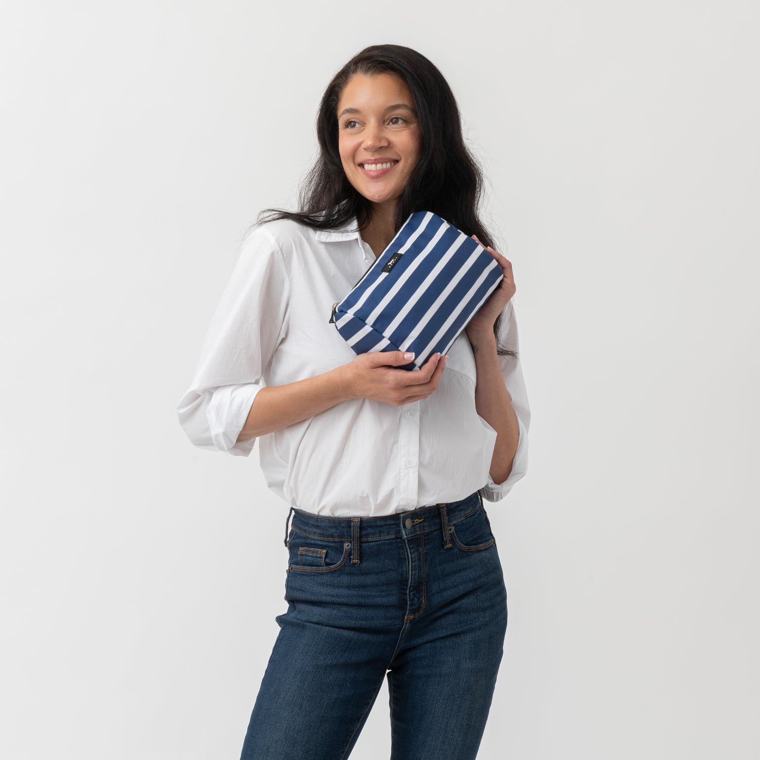 Woman holding a blue and white striped clutch against a plain background