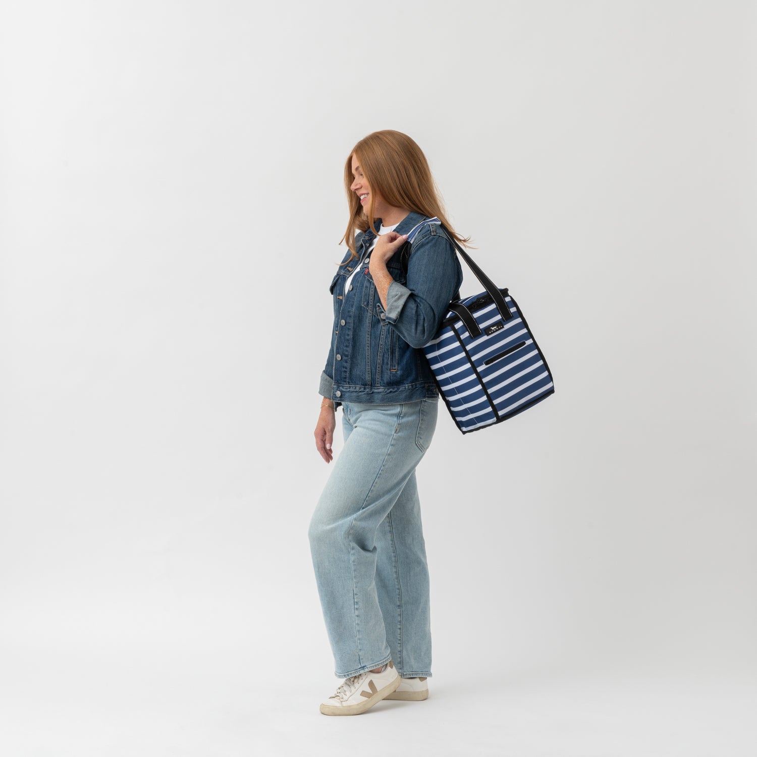 Woman holding a striped tote bag against a white background