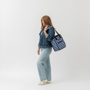 Woman holding a striped tote bag against a white background