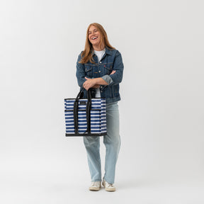 Woman holding a striped tote bag against a white background