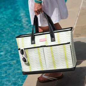 Person holding a patterned tote bag by a poolside