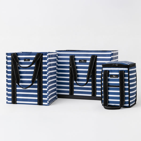 Three striped soft-sided bags in blue, navy, and white with black handles and trim, arranged on a light gray studio background.