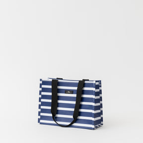Blue and white striped tote bag with black handles on a light gray background