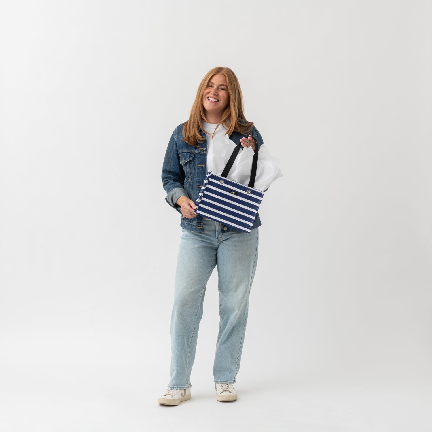 Woman holding a striped bag against a white background